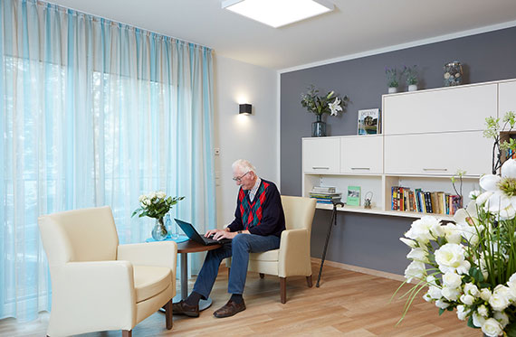 Rentner an einem Tisch mit Laptop